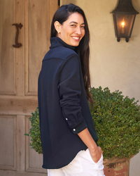 Woman in a Eileen Relaxed Button Up in British Royal Navy Triple Fleece from Frank & Eileen, smiling over her shoulder outdoors.