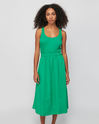 A woman posing in a green racerback Sadelle Clean Combo Midi in Island Time dress made of organic cotton against a white background by Nation LTD.
