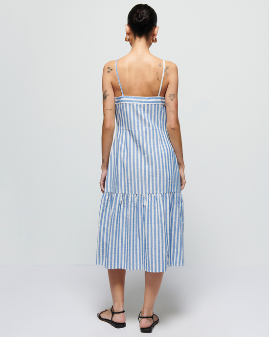 Woman in a Luciana Stripe Single Tier Dress in Parisian Blue by Nation LTD, viewing from the back, standing against a plain background.