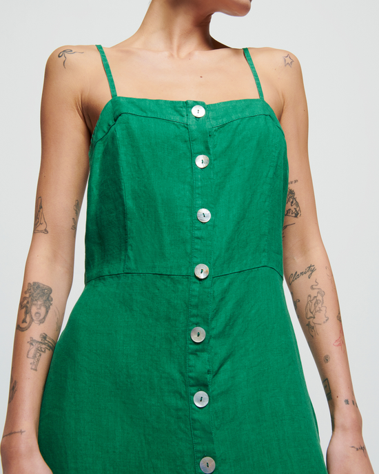 Close-up of a woman in a green Nation LTD Luciana Single Tier Dress in Verdant Green with a buttoned front, showing tattoos on her arms.