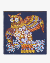 A colorful illustration of an owl with intricate patterns on a luxury accessory, a silk bandana from Inoui Editions, against a blue background.