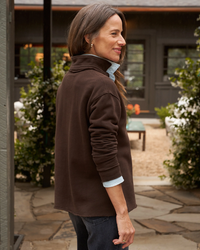 Woman in a Frank & Eileen Patrick Henley in Irish Chocolate Terry popover and blue shirt standing outside on a patio.