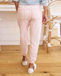 Person standing in a kitchen wearing pale pink Frank & Eileen Eamon Jogger Sweatpants in Vintage Rose and white slippers.