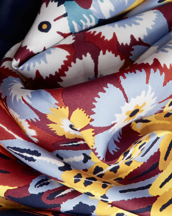 Close-up of a colorful floral silk bandana with folded layers of the Square / Carre 65 Hulule in Navy by Inoui Editions.