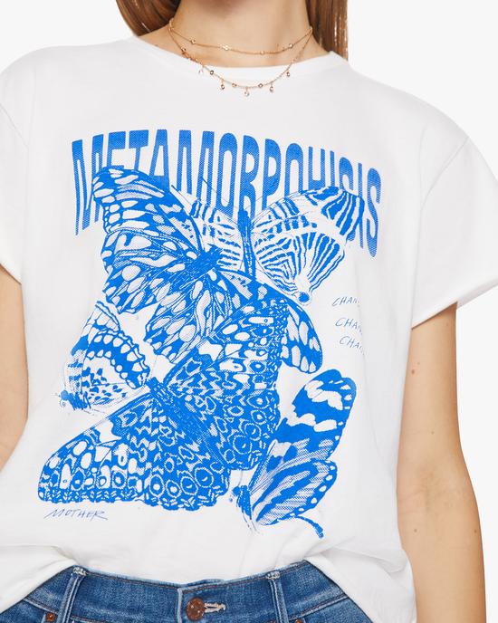 A person wearing a 100% Cotton Mother Tee with a blue graphic of butterflies and the word "metamorphosis" printed on it.