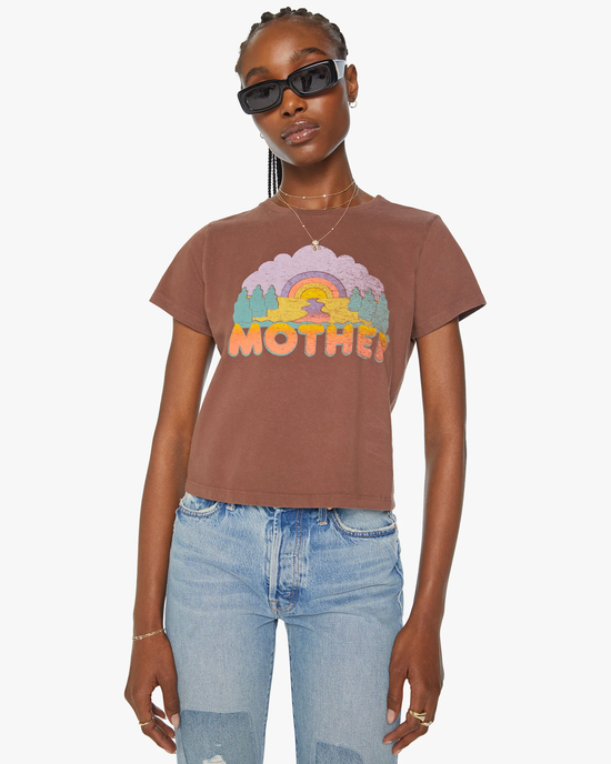 Woman wearing a Mother Denim The Boxy Goodie Goodie in Mother Sunset graphic crewneck t-shirt with the word "mother" and sunglasses, posing against a white background.