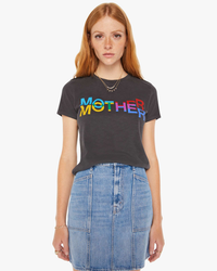 A woman in The Lil Sinful tee from Mother, with the word “mother” printed on it, paired with a blue denim skirt from Mother Denim.