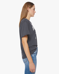 Side profile of a woman wearing a grey Mother Was A Punk Tee and blue Mother Denim jeans.
