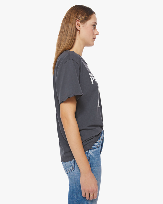 Side profile of a woman wearing a grey Mother Was A Punk Tee and blue Mother Denim jeans.