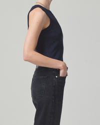 A person standing sideways wearing a dark Citizens of Humanity Isabel Rib Tank in Navy and black jeans.