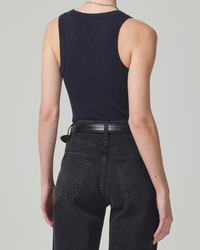 Woman wearing a blue Isabel Rib Tank in Navy made of organic cotton, tucked into high-waisted dark jeans from Citizens of Humanity with a black belt.