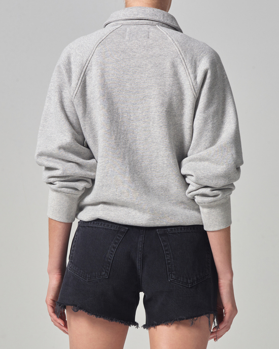 Woman standing with her back to the camera wearing a gray Organic Cotton Phoebe Pullover sweatshirt in Heather Grey and black denim shorts from Citizens of Humanity.
