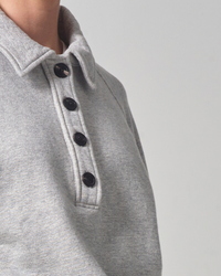 Close-up of a person wearing a Citizens of Humanity Phoebe Pullover in Heather Grey with dark buttons.