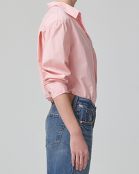 Side view of a person wearing a fitted silhouette pink Kayla Shrunken in Roselle shirt and blue jeans from Citizens of Humanity against a neutral background.