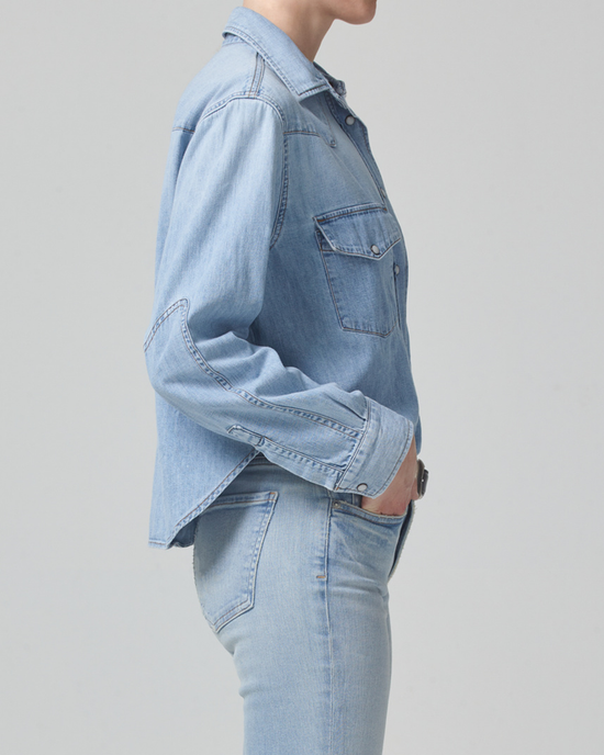 Person wearing a Citizens of Humanity Cropped Western Shirt in Pharos and high waist denim jeans, standing sideways against a neutral background.