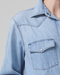 Close-up of a person wearing a light blue Cropped Western Shirt in Pharos by Citizens of Humanity with a focus on the pocket and collar details.