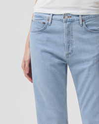 Close-up of a person wearing light blue high rise AGOLDE Parker Jeans in Pivot with a white top, focusing on the waist and pocket area.