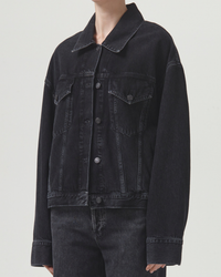 A person wearing a black AGOLDE Martika Jacket in Spider with a button-up front and flap pockets, crafted from non-stretch denim.