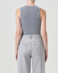 Rear view of a person wearing a sleeveless gray AGOLDE Poppy Scoop Neck Tank in Mirror Ball and light gray jeans, focusing on the outfit details.