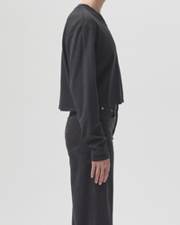 Person wearing a black AGOLDE Mason Cropped Tee in Marker and dark AGOLDE pants, viewed from the side, made of Organic Cotton.