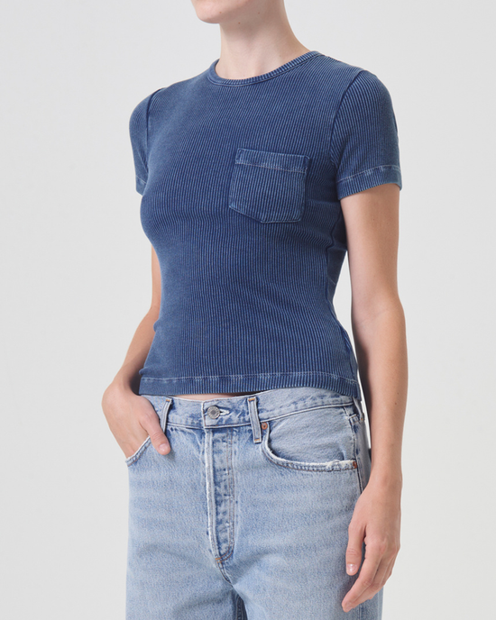 Woman in an AGOLDE Arlo Rib Pocket Tee in Indigo and light blue jeans, standing against a white background.