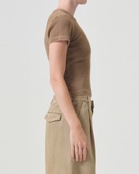 Side profile of a person wearing a fitted AGOLDE Arlo Rib Pocket Tee in Bamboo and beige cargo pants standing against a plain background.