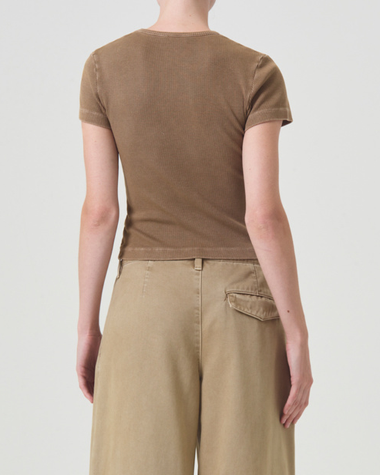 Rear view of a person wearing a brown AGOLDE Arlo Rib Pocket Tee in Bamboo and beige trousers with a visible pocket, standing against a white background.
