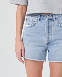 A person wearing AGOLDE Dee Short in Hazard high rise denim shorts with their hand resting on their hip.