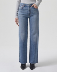 Woman standing in blue AGOLDE Harper Straight Jean in Flash made from a recycled cotton blend, featuring a mid-rise straight leg and black shoes.