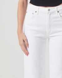 Close-up of a person wearing AGOLDE Harper Crop in Sour Cream jeans, hand resting casually on the hip.