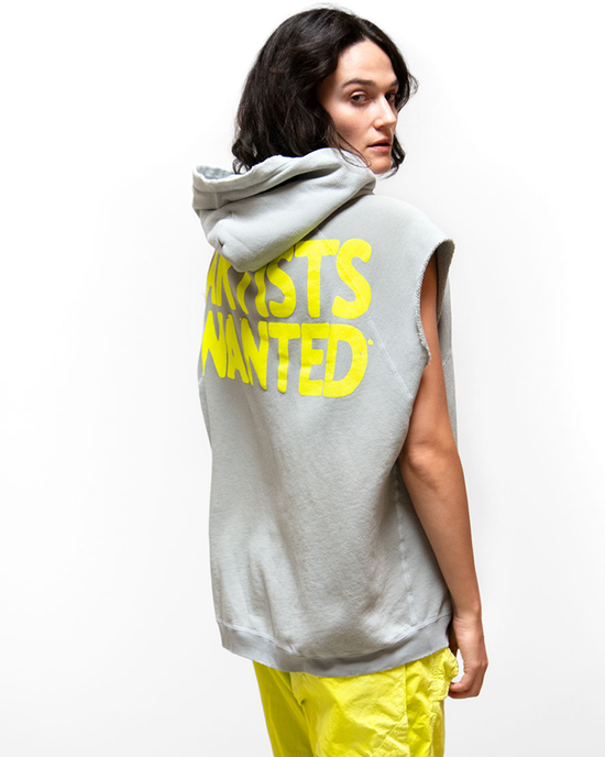 Woman in a AW Cutoff Superyumm Biggie Hoodie in Silver Rock from the Free City loungewear collection with "artists wanted" print, looking over her shoulder, against a white background.