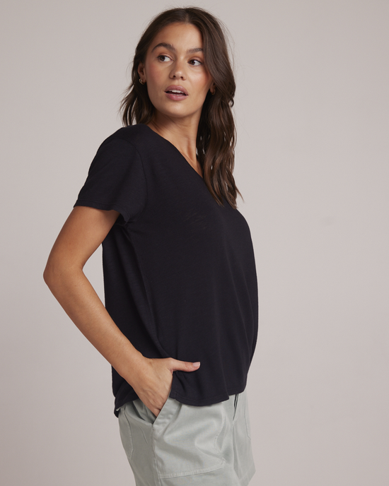 Woman in a casual black Bella Dahl Side Slit V Neck Tee and light-colored pants posing with one hand on her hip.