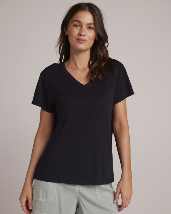 Woman wearing a Bella Dahl Side Slit V Neck Tee in Black made of 100% cotton and light-colored pants.