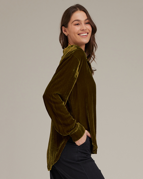 Woman in a Bella Dahl Long Sleeve Clean Shirt in Olive Gold smiling over her shoulder.