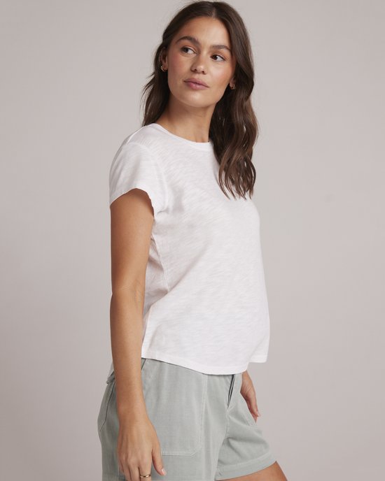 Woman wearing a white Bella Dahl Baby Crew Tee and casual shorts standing against a neutral background.