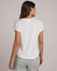 A woman seen from behind wearing a white Bella Dahl Baby Crew Tee and grey shorts.