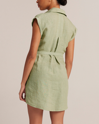 A woman wearing a Bella Dahl Belted Tunic Shirtdress in Pale Palm with a cut-out back and tie detail.