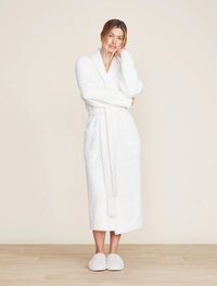 Woman standing in a Barefoot Dreams Cozychic Solid Robe in Pearl and slippers.