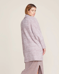Woman in a Barefoot Dreams CC Collared Poncho in HE Almond/Deep Taupe and skirt posing sideways.