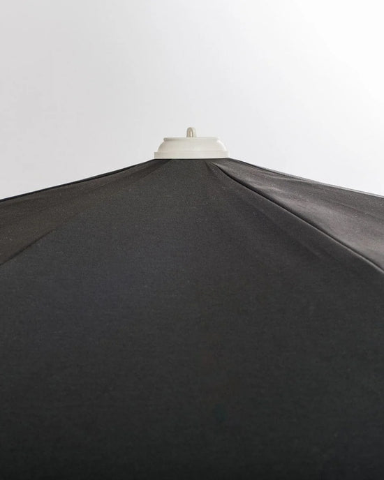 A close-up of the Amalfi Umbrella - Rivie Black by Business & Pleasure Co, featuring a UV and water-resistant canopy, shown against a plain light background.