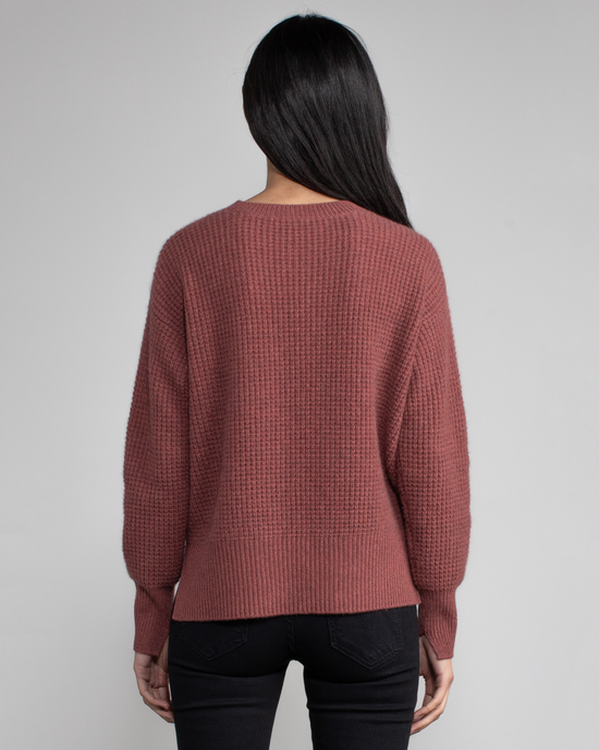 Woman standing with her back to the camera wearing a cinnamon-colored Margaret O'Leary Nora Pullover and black pants.