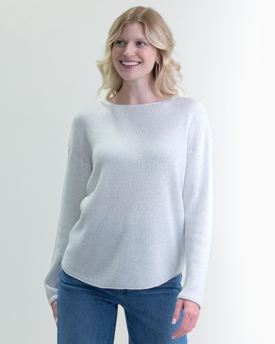 Woman smiling in a Margaret O'Leary Shirttail Easy Boatneck in Ivory/Salt and blue jeans against a neutral background.