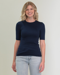 Woman in a Margaret O'Leary Knit Rib Tee in Navy and light blue jeans smiling at the camera.