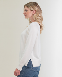 A woman in profile wearing a Margaret O'Leary Livia Pullover in Ivory and jeans.