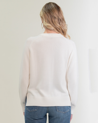Woman seen from behind wearing a white Margaret O'Leary Livia Pullover in Ivory and blue jeans.
