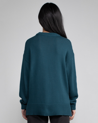 Woman standing with her back to the camera, wearing a Margaret O'Leary Chelsea Pullover in Pine in a relaxed fit.