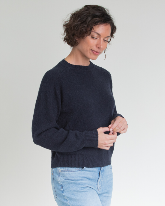 Woman buttoning her Lola Pullover in Navy by Margaret O'Leary.