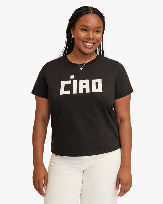 Smiling woman wearing a Clare V. Block Ciao Classic Tee in Black w/ Cream and white pants, standing against a plain background.