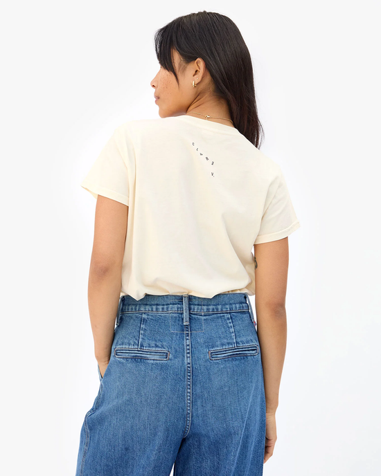 A woman seen from behind wearing a casual ivory crew neck Clare V. Oui Classic Tee in Cream w/ Black and blue denim jeans.