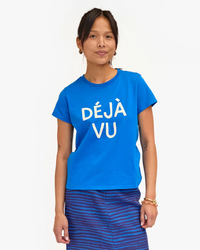 Woman in a blue Clare V. Deja Vu Classic Tee in Bright Cobalt with Cream and striped skirt, standing with hands at sides, looking at the camera.